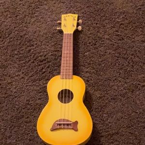 This is a regular sized ukulele. It’s yellow and brown, with a dolphin on it!